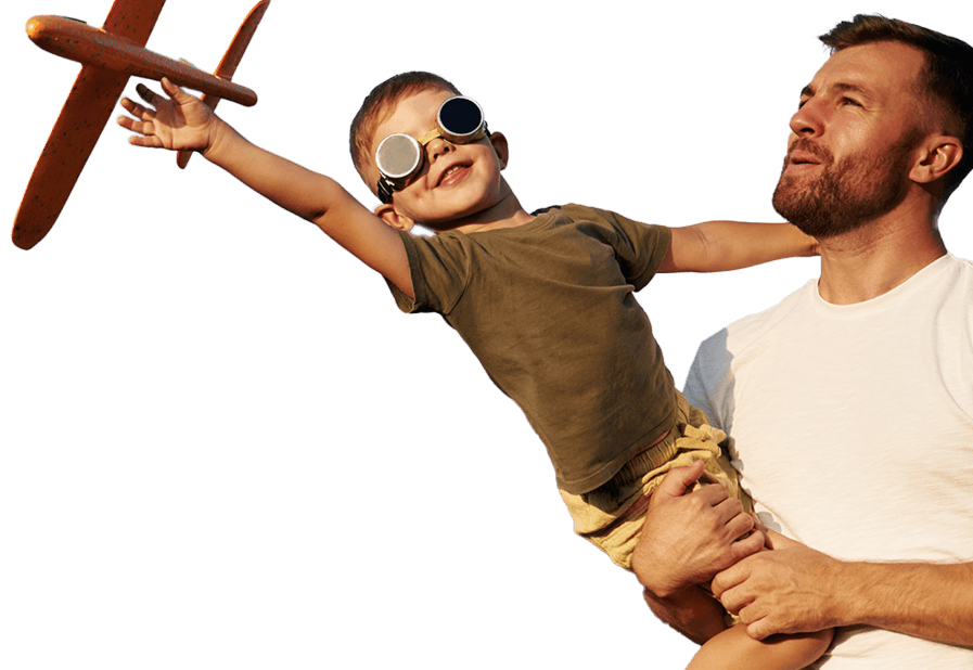 A child playing with a wooden toy aeroplane with a father holding him looking upwards