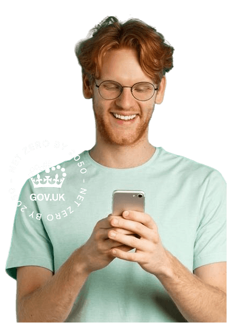 A middle-aged man smiling while looking down at his phone with the Gov UK Net Zero badge to the left